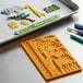 A tray with a Wilton Jungle Silicone Fondant and Gum Paste Mold and tools on a table.