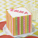 A cake with a name on it on a plate with yellow and white Wilton Letters and Numbers silicone mold packaging.