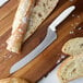 A Dexter-Russell cutlery set with a knife and bread on a cutting board.