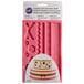 A pink Wilton silicone mold with ribbon and fabric shapes.