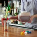 A woman using a Vollrath Bar Keep II pour container to pour a drink into a glass.