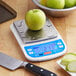 A digital portion control scale with a green apple on its stainless steel weighing platform.