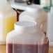 A white plastic Vollrath container with a brown liquid and a white lid on a counter.