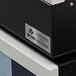 A black printer with a white Avery label on it.