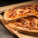 A Rich's pepperoni pizza being cut on a wooden board.