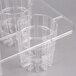 A clear plastic rack with four compartments holding clear plastic containers.