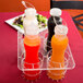 A clear plastic rack holding four salad dressing bottles.