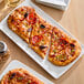 A plate with a slice of pizza on Rich's oval flatbread crust.