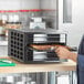 A person holding a Backyard Pro Butcher Series food dehydrator tray full of food.