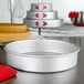 A round silver Fat Daddio's cake pan on a table.