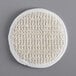 A white round Novo Essentials bath loofah with a woven surface.