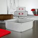 A white square metal cake pan on a metal surface.
