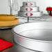 A close-up of a round silver Fat Daddio's cake pan on a counter.