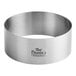 A stainless steel round cake ring mold on a counter.