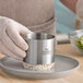 A stainless steel round cake and food ring mold being used to shape food on a plate.