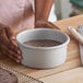A round, straight-sided anodized aluminum cake pan filled with chocolate batter.