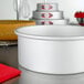 A round anodized aluminum cake pan on a white counter.