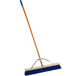 A Carlisle blue broom with a wooden handle.