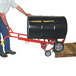 A man pushing a barrel on a red Wesco hand truck.