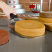 A hand using the Fat Daddio's stainless steel cake lifter to lift a round yellow cake.