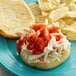 A close-up of a sandwich with Frank's RedHot Buffalo Sauce on a blue plate with ketchup and potato chips.