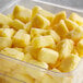 A plastic container of IQF pineapple chunks on a counter.