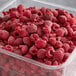 A plastic container of whole and pieces of IQF raspberries.