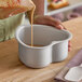 A heart-shaped anodized aluminum cake pan being filled with batter.