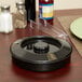 A black circular Carlisle polypropylene container with a black interlock lid on a table.