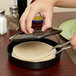 A person using a Carlisle black tortilla server to cut a tortilla on a plate.