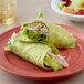 A plate with a chicken wrap made with Father Sam's Garden Spinach Tortilla on a table.