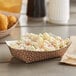 A bowl of macaroni salad in a yellow Carnival King paper food tray on a table.