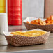 A table with Carnival King paper food trays holding fries and drinks.