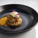 A black bowl with flowers on top of food.
