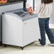 A woman standing next to a Galaxy curved top display freezer.