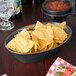 A large oval basket filled with tortilla chips on a table in a Mexican restaurant.