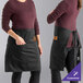 Two women wearing black Mercer Culinary short bistro aprons with the word "Genesis" on them.