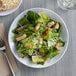 A plate of salad with croutons and parmesan cheese on a Acopa Lunar melamine plate.