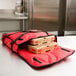 A red American Metalcraft pizza delivery bag holding pizza boxes.