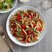 A plate of pasta with tomatoes and salad on a white Acopa Lunar melamine plate.