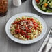 A white Acopa Foundations melamine plate with pasta and salad on a table.