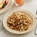 An Acopa Foundations narrow rim melamine plate with hash browns on a table.