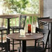 A Lancaster Table with Textured Walnut Finish with chairs and a drink on it.