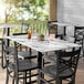 A Lancaster Table & Seating rectangular table with a marble top and chairs with drinks on it.