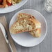 A white Acopa Lunar melamine plate with a piece of bread and a plate of food with a knife and fork on a table.