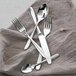 A Fortessa stainless steel serving fork on a table with other silverware.