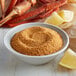A bowl of J.O. No. 2 Crab Seasoning on a table with crab legs and lemon slices.
