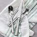 A Fortessa silverware set on a green towel with a knife and spoon.