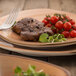 A brown oval porcelain plate with a fork and knife serving a meal.
