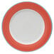A close-up of a bright white porcelain plate with a coral and blue rim.